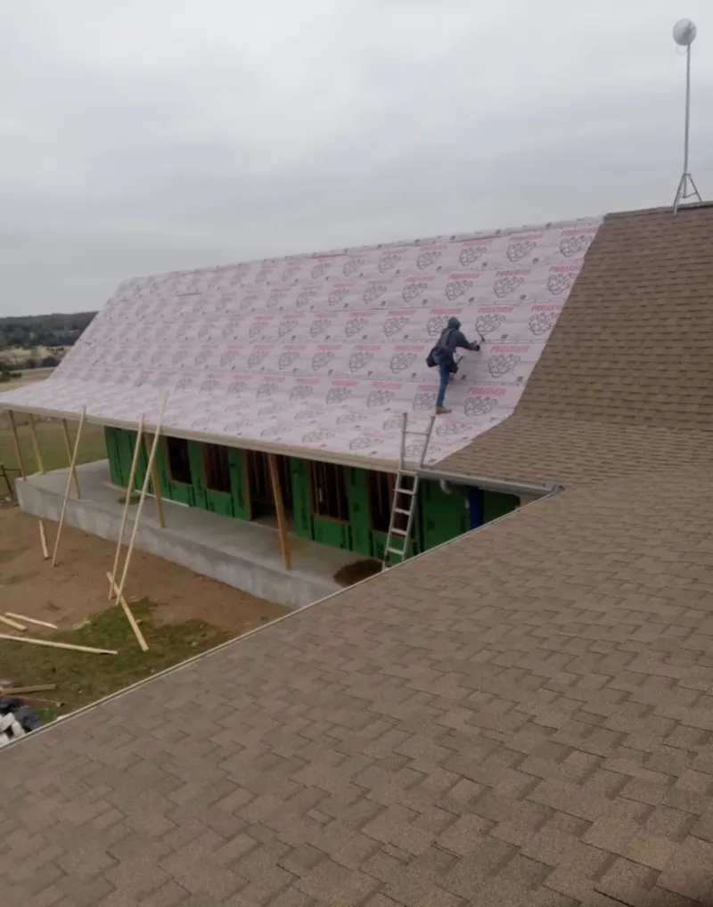Worker preparing underlayment for a metal roof installation in West Bradford